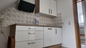 A kitchen with white cabinets, a coffee maker, and a television mounted above the counter. - Apartment 'Ferienwohnung Auf Der Heide' with Shared Terrace, Shared Garden and Wi-Fi (Großschönau)