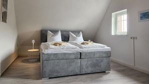 A bedroom with a bed, a lamp, a window, and a ceiling light. - Apartment 'Ferienwohnung Auf Der Heide' with Shared Terrace, Shared Garden and Wi-Fi (Großschönau)