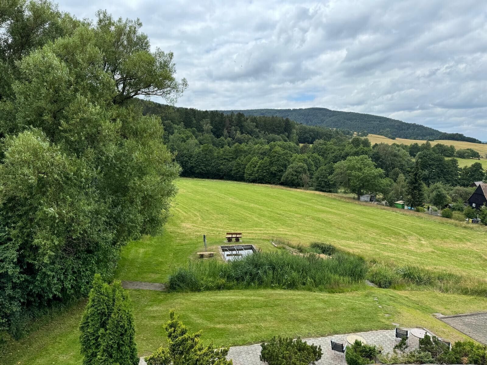 A rural landscape with a grassy field, a picnic table, and a small building.