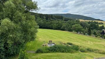 Un paisaje rural con un campo cubierto de hierba, una mesa de picnic y un edificio pequeño.