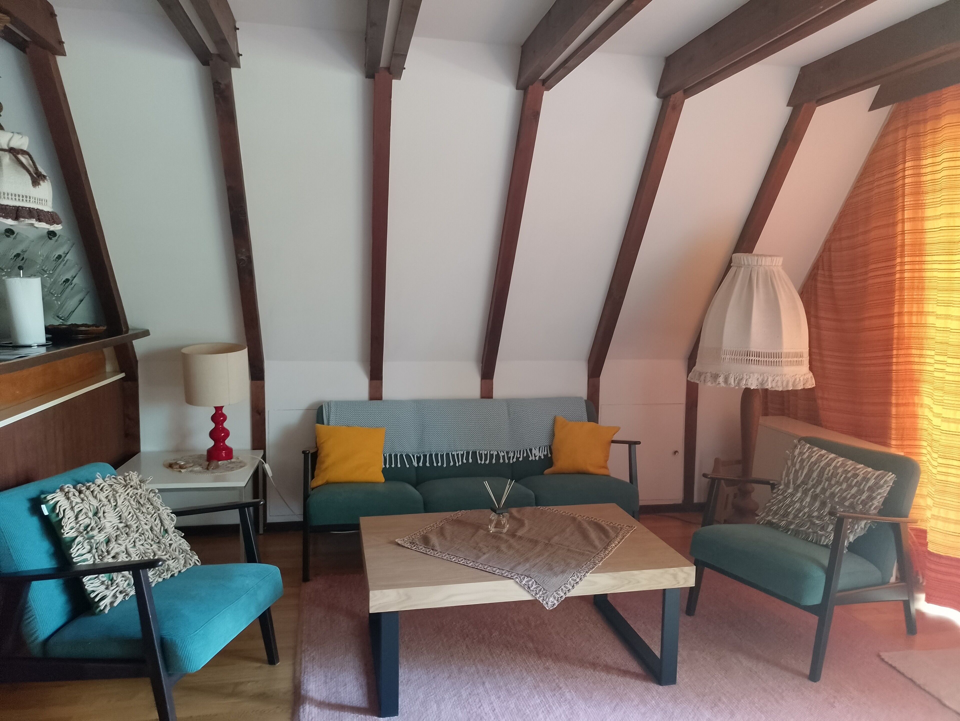 Une pièce chaleureuse avec un plafond en bois, un canapé avec des coussins, une table basse et une lampe.