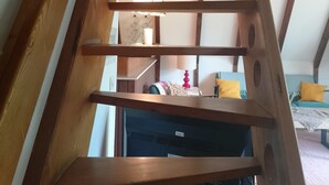 A wooden spiral staircase with a ceiling fan, a television, and a lamp in the background. - Holiday Home 'Bergwiese' with Mountain View, Private Garden and Balcony (Siegsdorf)