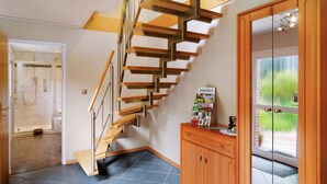 Ein modernes Interieur mit einer Holztreppe, einer Glastür mit Blick und einem Fliesenboden.