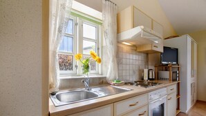 Una cocina con pileta, estufa, horno microondas y placares.