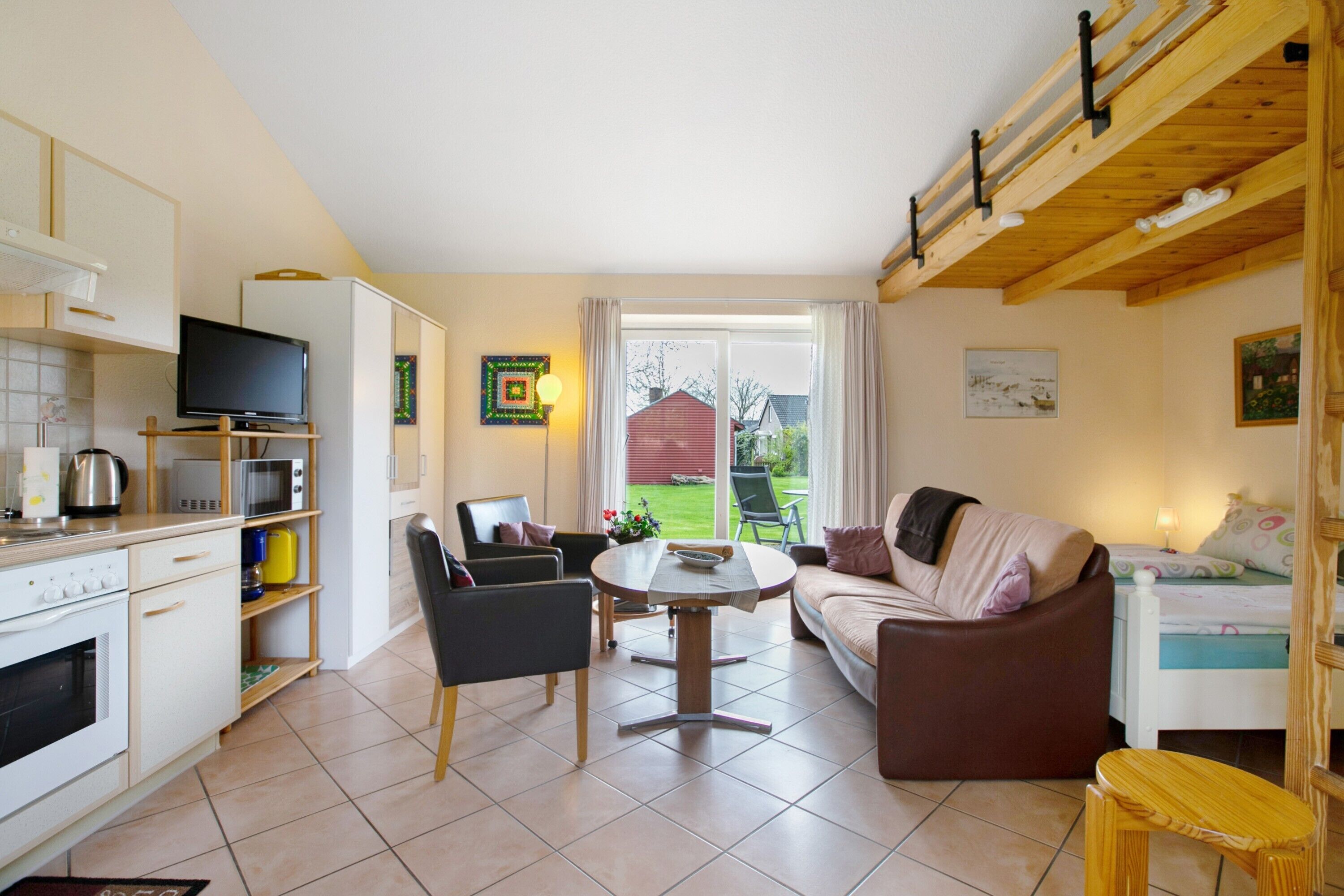A well-lit room with a kitchen, dining area, and living space. There is a television, a dining table, and a sofa.