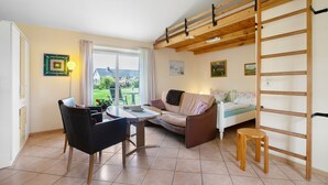 Una habitación con una mesa de comedor, sillas, un sofá, una escalera y vistas al exterior.