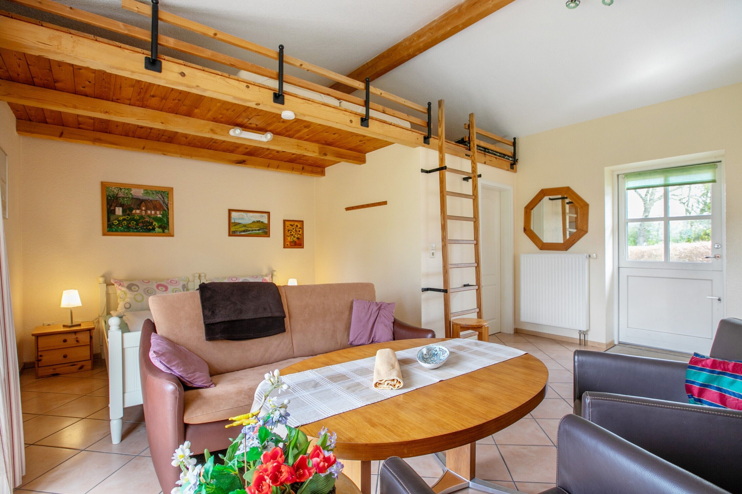 Una sala de estar acogedora con techo de madera, un sofá, una mesa con camino de mesa y una ventana con vistas.