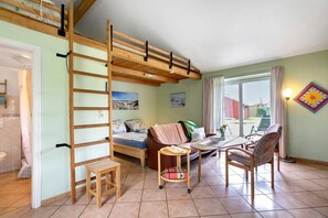 Une pièce comprenant un lit en mezzanine, un canapé, une table à manger et des chaises.