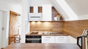 Una cocina moderna con encimera de madera, horno empotrado y armarios blancos.