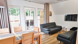 Una sala de estar moderna con un sofá, una mesa de comedor, sillas y un televisor.