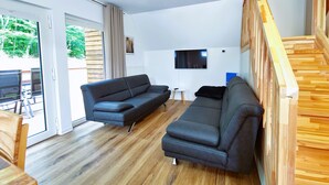 Una sala de estar moderna con un sofá, un televisor y una escalera.