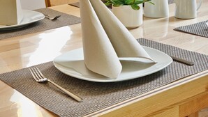 Una mesa de comedor con un plato, un tenedor, un cuchillo, una jarra y una planta pequeña.