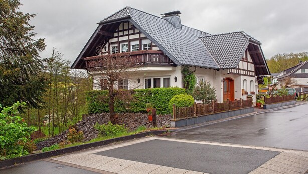 A traditional half-timbered house with a steeply pitched roof, stone foundation, and a wooden fence. - Apartment 'Hönneblick' with Private Terrace, Private Garden and Wi-Fi (Balve)