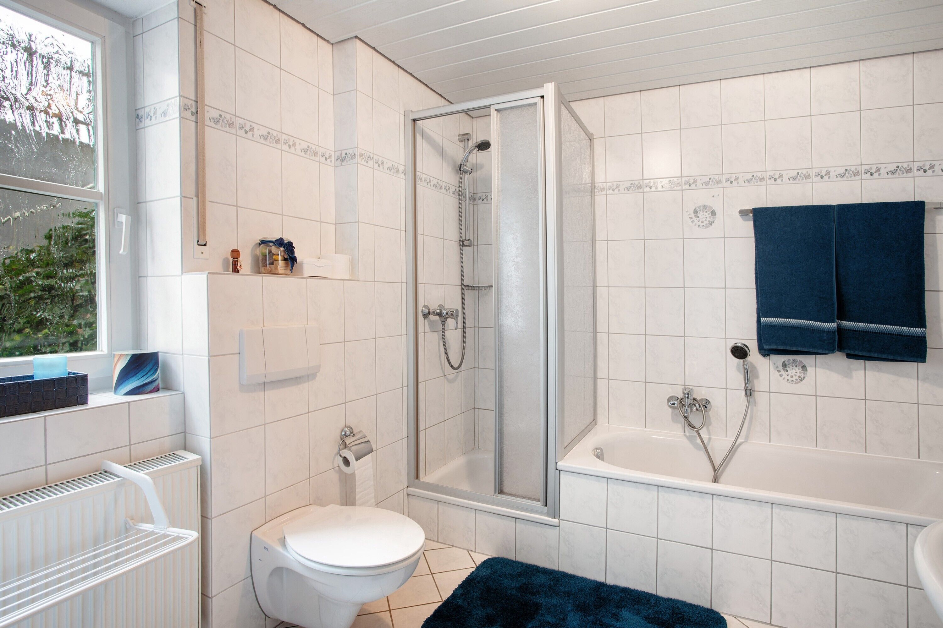 Ein Badezimmer mit Toilette, Dusche, Badewanne und Fenster.