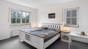 A bedroom with a bed, bedside tables, a desk, and two windows. - Apartment 'Hönneblick' with Private Terrace, Private Garden and Wi-Fi (Balve)