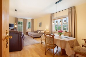 A room with a dining table, chairs, a sofa, and a television.