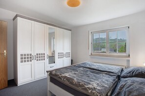 A bedroom with a bed, wardrobe, and a window with a view.