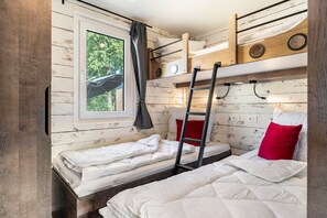 Ein kleines Zimmer mit Etagenbetten, einem Fenster mit Blick und einer Treppe.