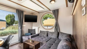 Een moderne woonkamer met een modulaire bank, een salontafel, een aan de muur bevestigde televisie en een groot raam met gordijnen.