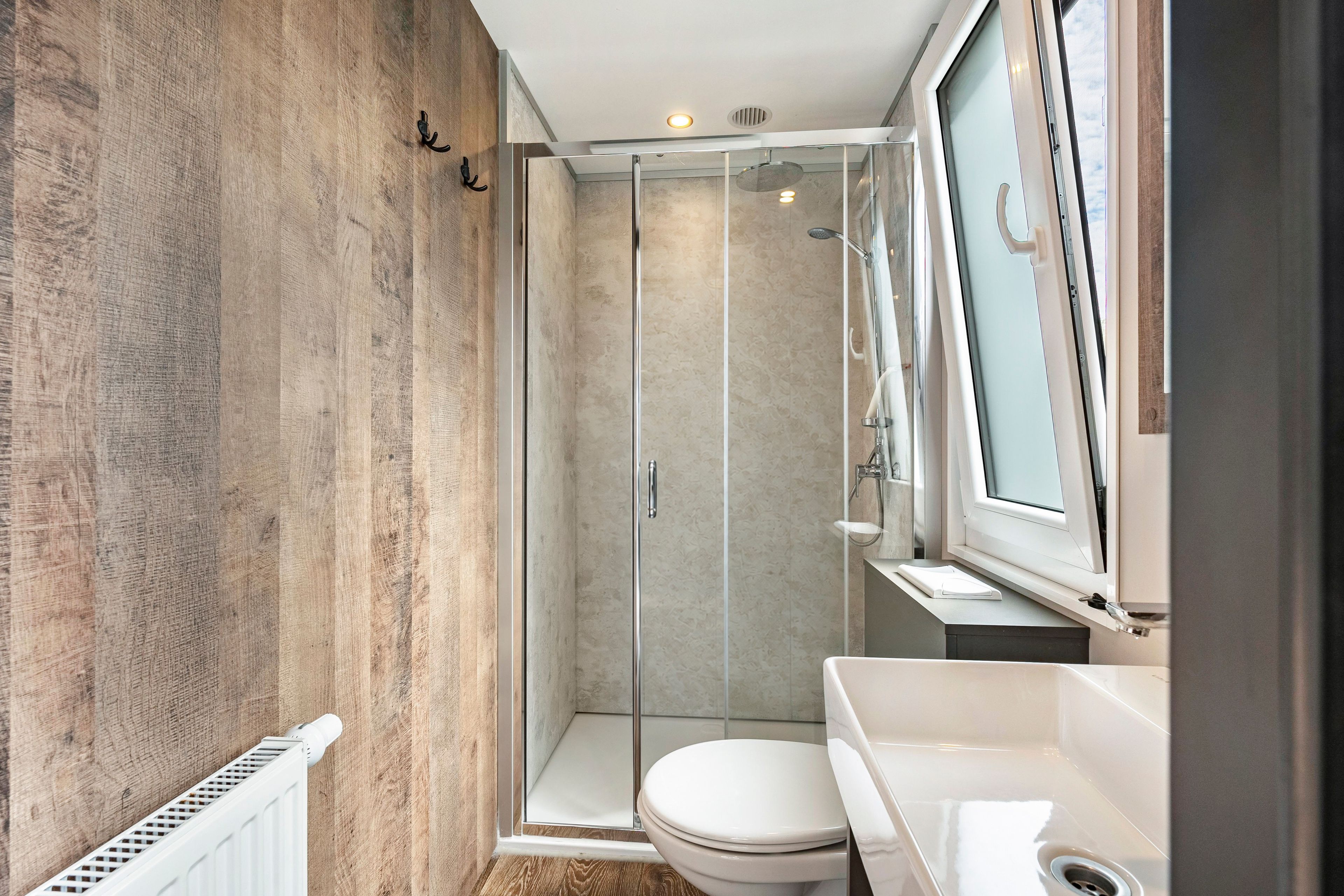 A modern bathroom with a glass shower enclosure, a white toilet, and a sink.
