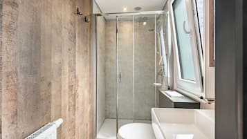 A modern bathroom with a glass shower enclosure, a white toilet, and a sink.