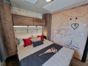 A bedroom with a wooden headboard, a map on the wall, and a bed with multiple pillows. - Holiday Home 'Kaperfahrt' with Private Terrace, Wi-Fi and Air Conditioning (Großenbrode)
