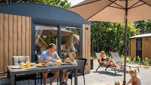 A modern outdoor dining area with a table, chairs, and a large umbrella. - Holiday Home 'Kaperfahrt' with Private Terrace, Wi-Fi and Air Conditioning (Großenbrode)