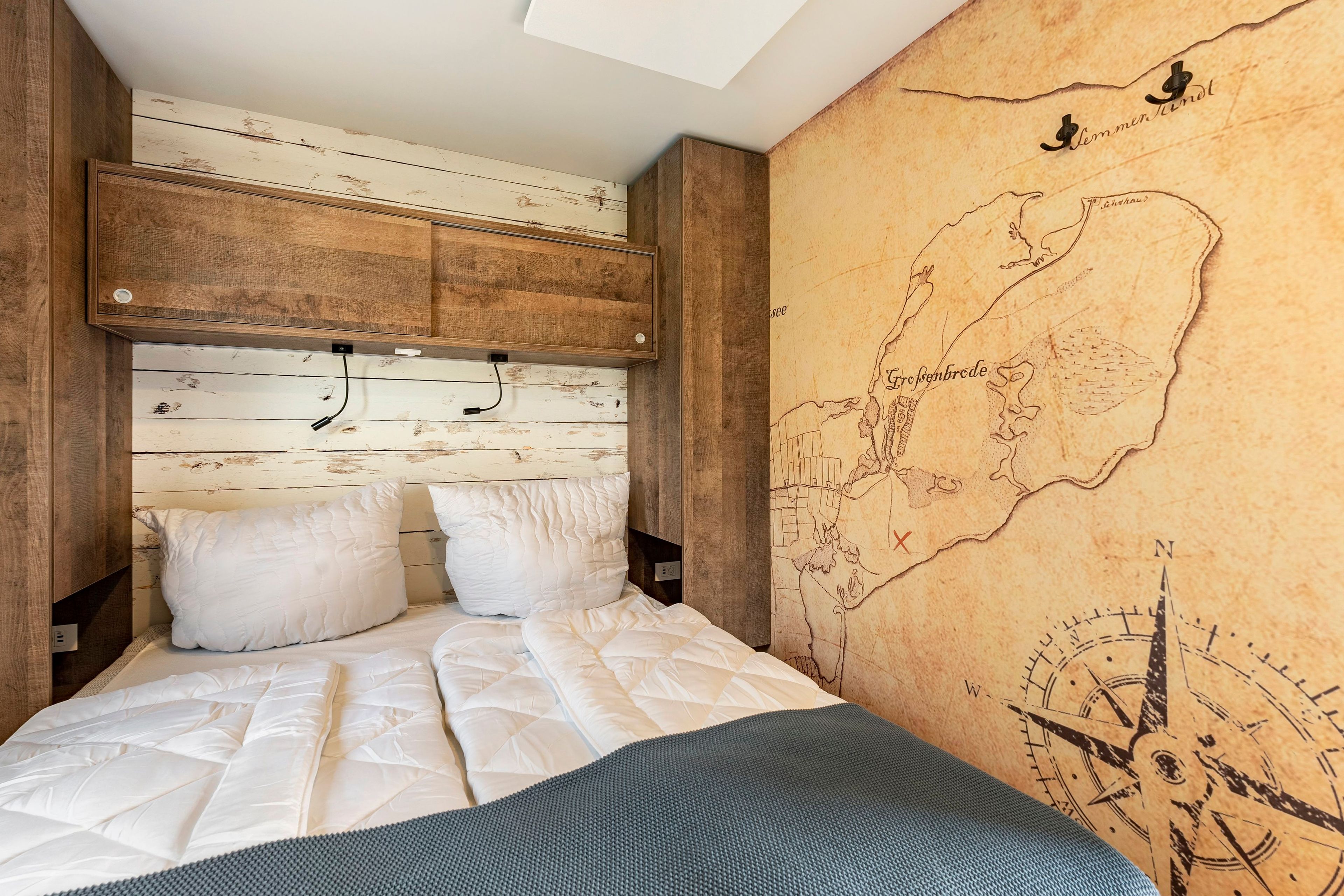 A bedroom with a wooden headboard, a map mural on the wall, and a bed with white bedding.