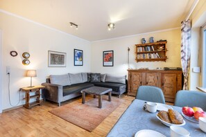 A living room with a sofa, coffee table, and a dining area with a table set for breakfast.