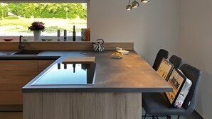 Una cocina moderna con una isla central, una ventana con vistas y lámparas colgantes.