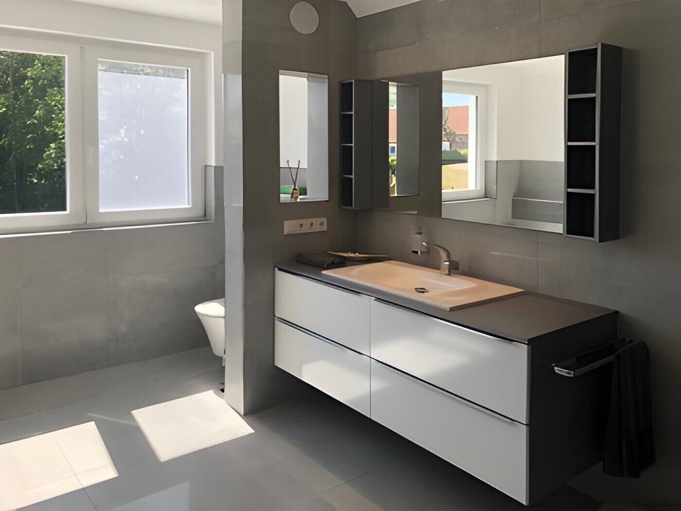 Un baño moderno con un espejo grande, un lavabo y un inodoro.