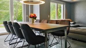 Un comedor moderno con una mesa larga, seis sillas y una lámpara central.