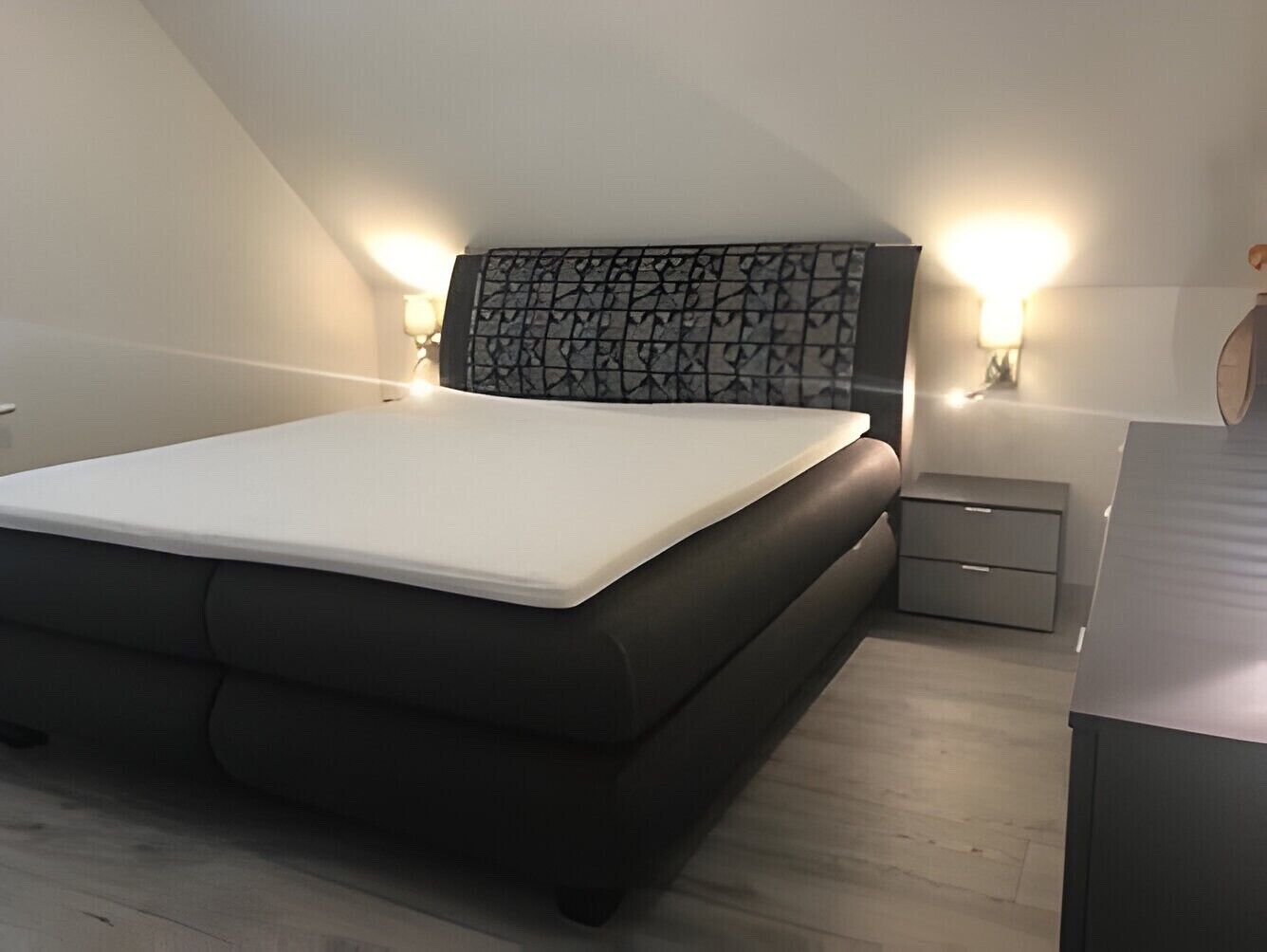 A bedroom with a bed, bedside tables, and a headboard.