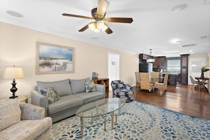 A living room with a sofa, armchairs, a glass coffee table, a ceiling fan, and a painting on the wall. - Gorgeous 2BR Residence with Pool and Spa at Margarita Mansion (Fort Myers Beach)