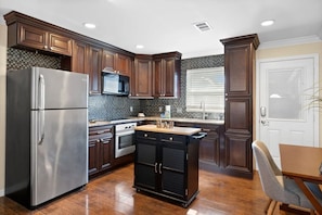 A kitchen with dark wood cabinets, stainless steel appliances, a tiled backsplash, and a window with blinds. - Gorgeous 2BR Residence with Pool and Spa at Margarita Mansion (Fort Myers Beach)