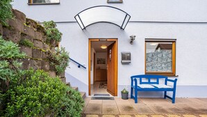 A building entrance with a wooden door, a blue bench, and a potted plant. - Holiday Apartment "Brigitte" with Mountain View & Wi-Fi (Forbach)