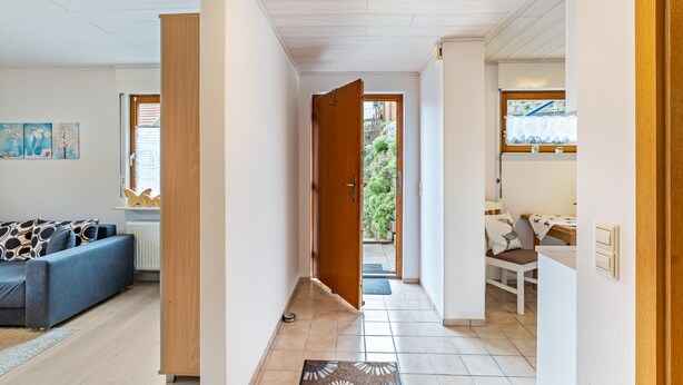 A modern interior with a sofa, a wooden door, a kitchen area, and a view to the outside. - Holiday Apartment "Brigitte" with Mountain View & Wi-Fi (Forbach)