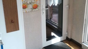 Een deur met een ruitje, een deurmat en een muur met een afbeelding van een margriet.