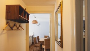 Ein Flur mit einem Holzkasten, einer Pendelleuchte, einem Spiegel und einem Essbereich mit Korbstühlen und einem Tisch.
