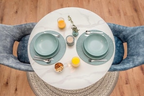 Enjoy a meal at a beautifully set table with a round table, matching plates, cutlery, and glasses.