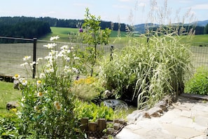 Un jardín con un estanque, una valla y vistas a un campo de golf.