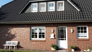 Ein zweistöckiges Haus mit einem dunkel gefliesten Dach, roten Backsteinwänden und Fenstern mit weißen Rahmen.