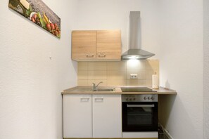 A compact kitchen with a sink, stove, oven, and wooden cabinets.