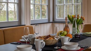 A dining table with a variety of food items, a bottle, and a vase with flowers. - Suite Wintergarten: Lake Access, Wi-Fi, Parking, 2 Bathrooms, Large Garden (Dedelstorf)