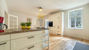 A modern kitchen with white cabinetry, a wooden countertop, a built-in oven, and a window with a view of trees. - Suite Wintergarten: Lake Access, Wi-Fi, Parking, 2 Bathrooms, Large Garden (Dedelstorf)