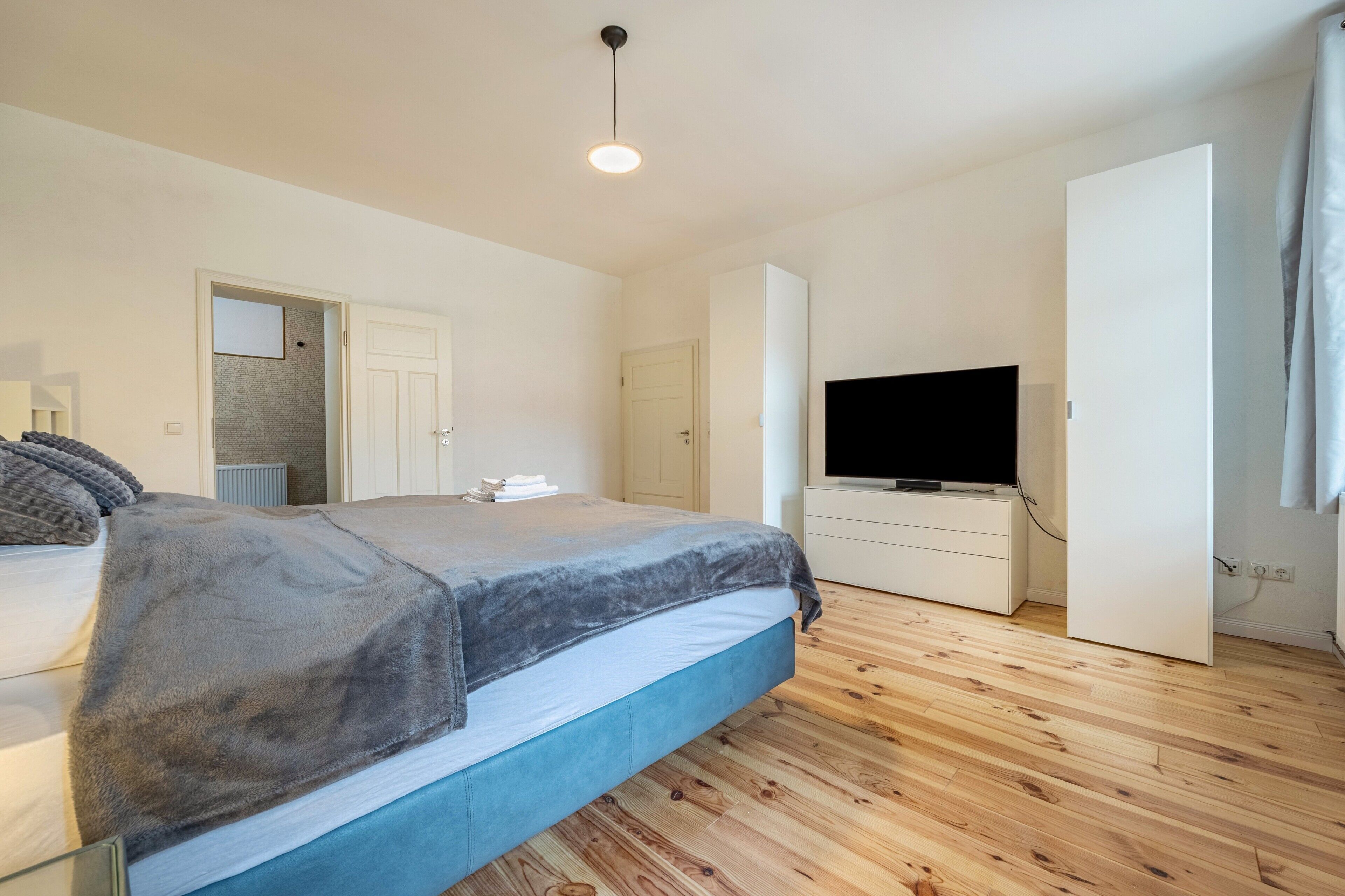 Un dormitorio con cama, televisión, armario y puerta.
