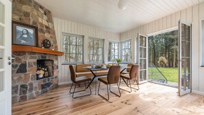 A dining area with a stone fireplace, wooden flooring, and large windows. - Suite Wintergarten: Lake Access, Wi-Fi, Parking, 2 Bathrooms, Large Garden (Dedelstorf)