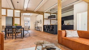 A spacious living area with a leather sofa, glass coffee table, and a dining set.