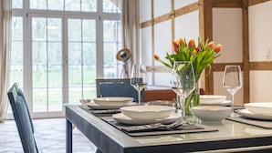 A dining table set with plates, bowls, and wine glasses, with a vase of tulips on the table.