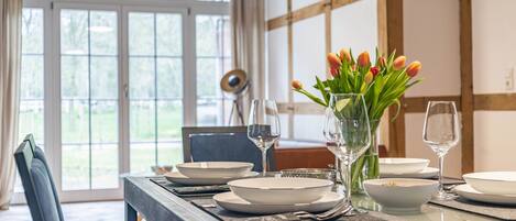 A dining table set with plates, bowls, and wine glasses, with a vase of tulips on the table.